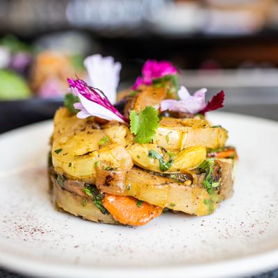 green tomatoes, carrots, and onions and colorful flowers on white plate