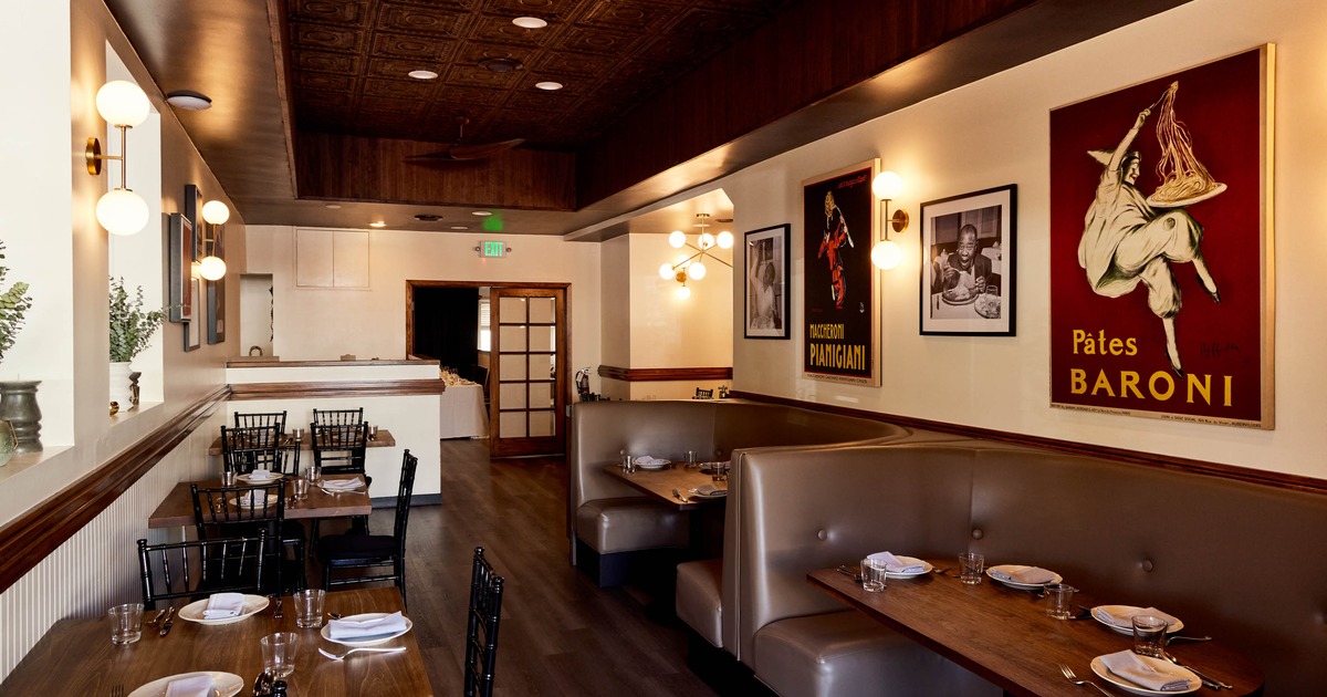 Interior of a restaurant with wooden tables, leather booths, vintage posters, and warm lighting