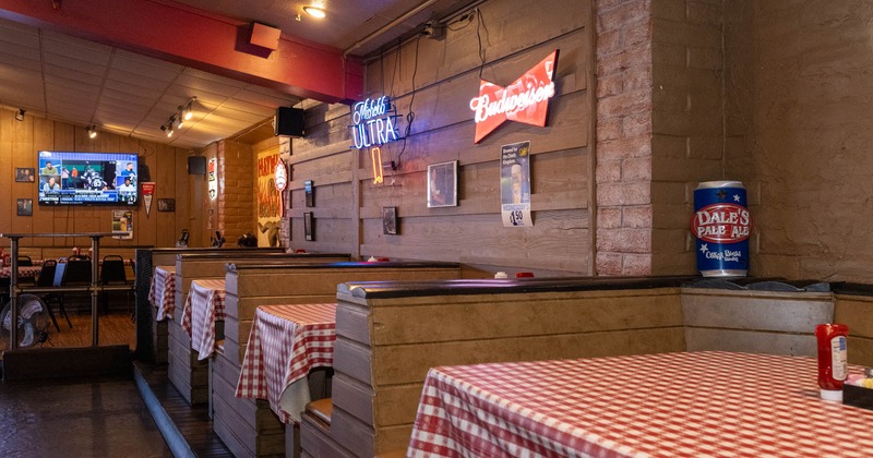 Interior, dining area, booths with checkered red and white table cloths, neon beer signs