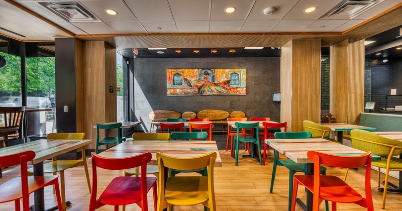 Vivid and cozy interior dining area with wooden tables and colorful chairs