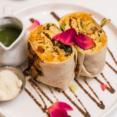 Breakfast burrito with sauce and cheese on the side.