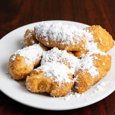 Fried dough dessert pastries topped with powdered sugar.