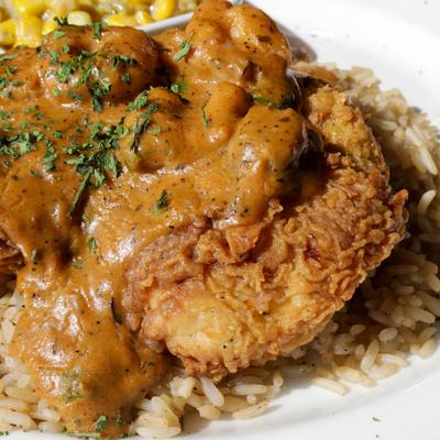 Fried and breaded chicken breast, in parmesan cream sauce, on a bed of rice.