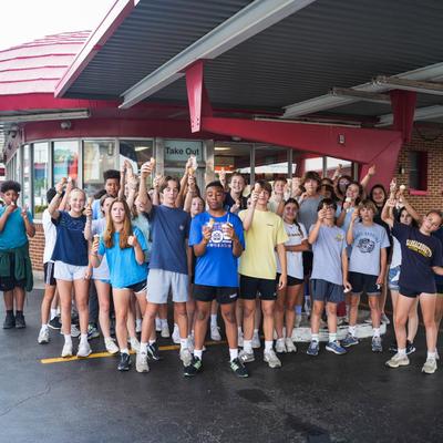 A crowd of young people holding ice creams outside Doumar's Cones & Barbecue.