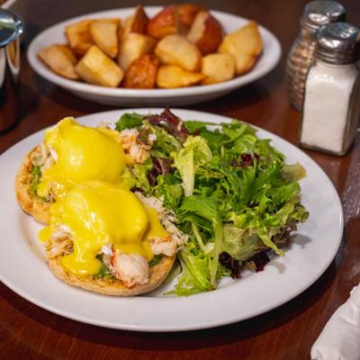Dungeness Crab Benedicts with mixed greens and a side of roasted potatoes.