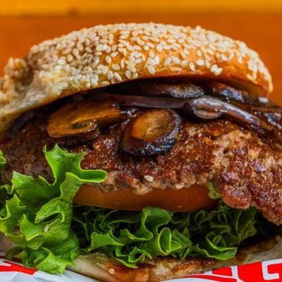 Impossible Burger topped with lettuce, tomato and mushrooms.