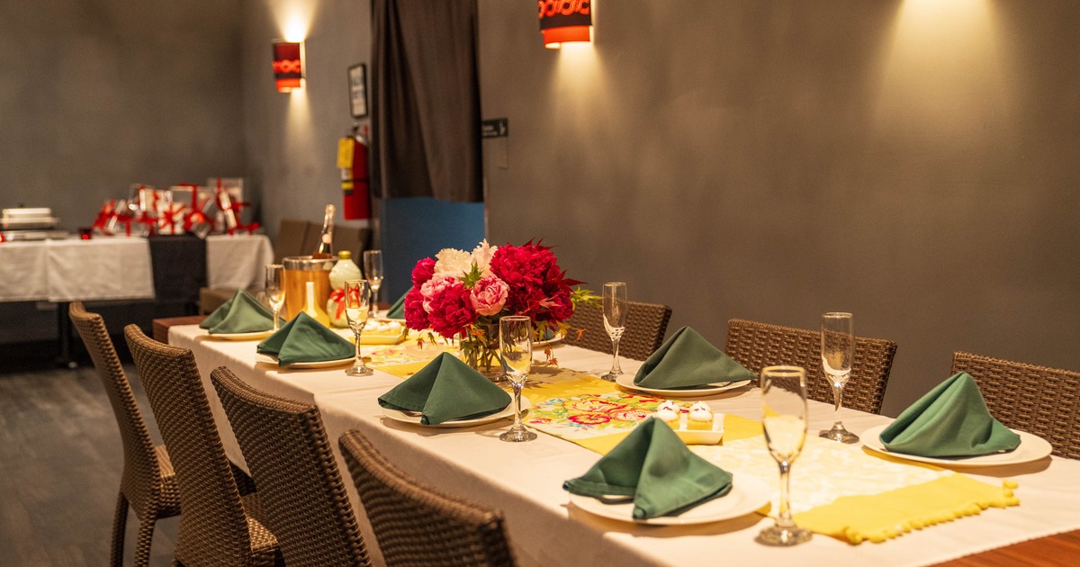 A formal dining room table setup with green napkins and floral centerpiece under warm lighting