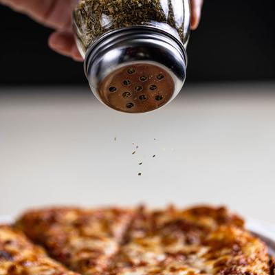 Seasoning a pizza, closeup