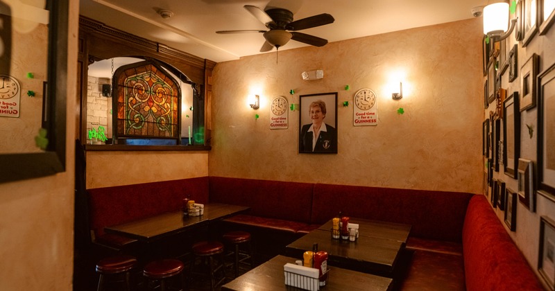 Interior - red cushioned seating, dark wooden tables, a stained glass window, Guinness-themed decor