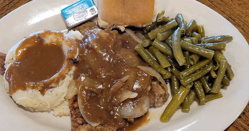 Country fried steak with mashed potato, green beans and a bread roll