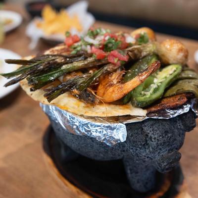 Molcajete, with shrimp, steak, chicken, cactus, and scallions.
