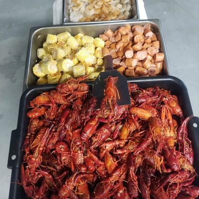 Crawfish boil with several trays with corn, sausage and shrimp.