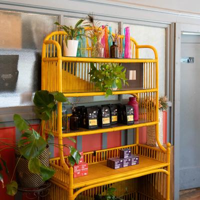 Yellow shelf with potted plants, coffee bags, and decorative bottles.