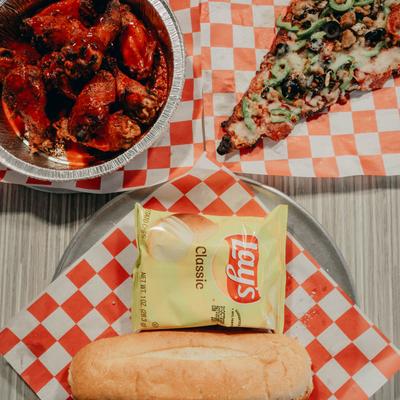 Buffalo wings covered in hot sauce, a slice of supreme pizza, and chicken Parmesan sub.