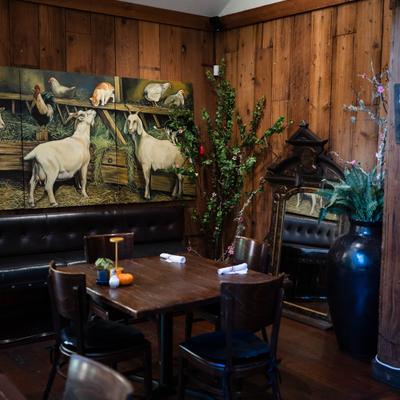 Dining area with wooden furniture, wood-paneled wall, potted plants and artwork.