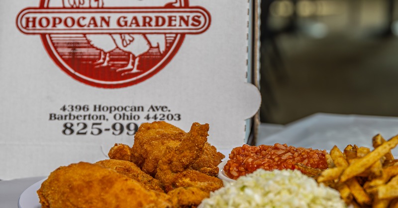 Fried chicken dinner plate displayed in front of restaurant’s branded takeout box