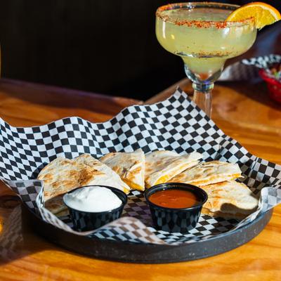 Quesadilla served with salsa and sour cream, accompanied with Margarita cocktail.