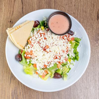 Greek salad with house dressing and pita bread on the side.
