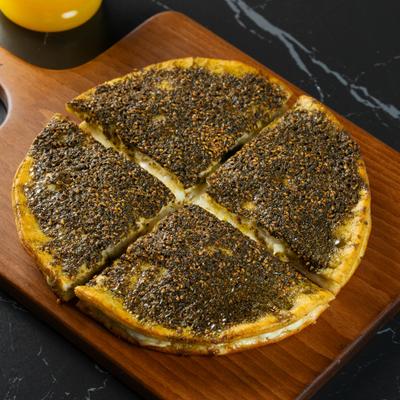 Sliced Lebanese flatbread covered in zaatar and sesame seeds.