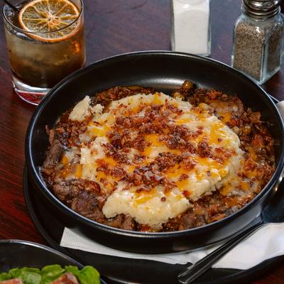 Shepherd pie in black bowl with melted cheese.