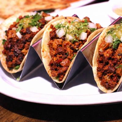 Campechano tacos topped with roasted tomatillo sauce and diced onion.