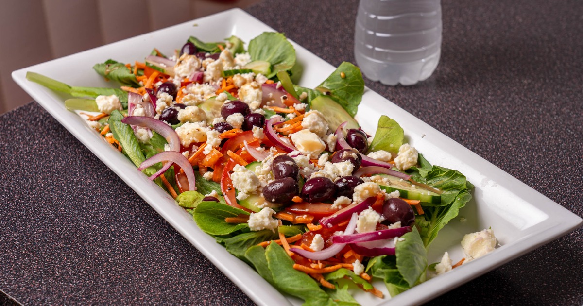 Greek salad topped with olives feta and sliced onions