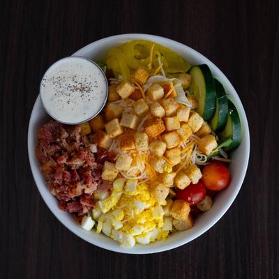 House Salad, with lettuce, tomato, cucumber, peppers, egg, bacon, cheddar, and croutons.