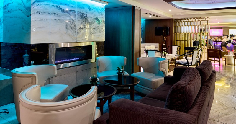 Interior modern lounge with cream leather chairs, dark wooden tables and a fireplace