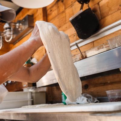 A person stretching pizza dough by hand.