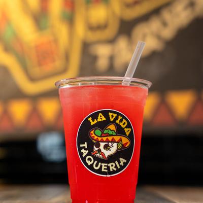 Red agua fresca  in a clear plastic cup featuring the circular sign.