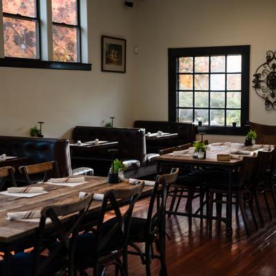 Dining area with a mix of table and booth seating, framed art and windows.