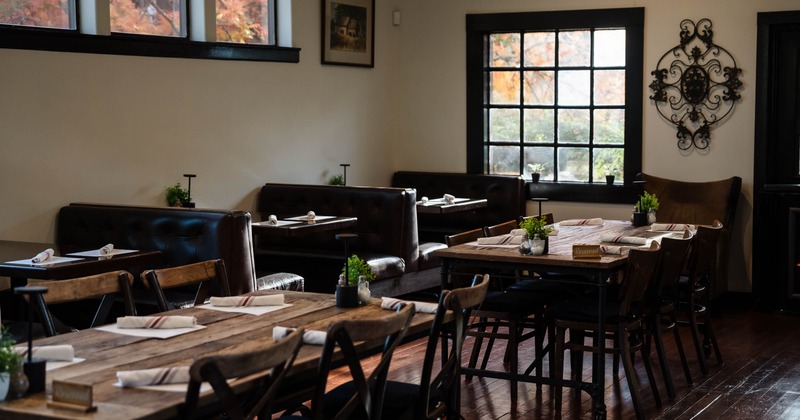 Restaurant interior with wooden tables, leather booths, and large windows