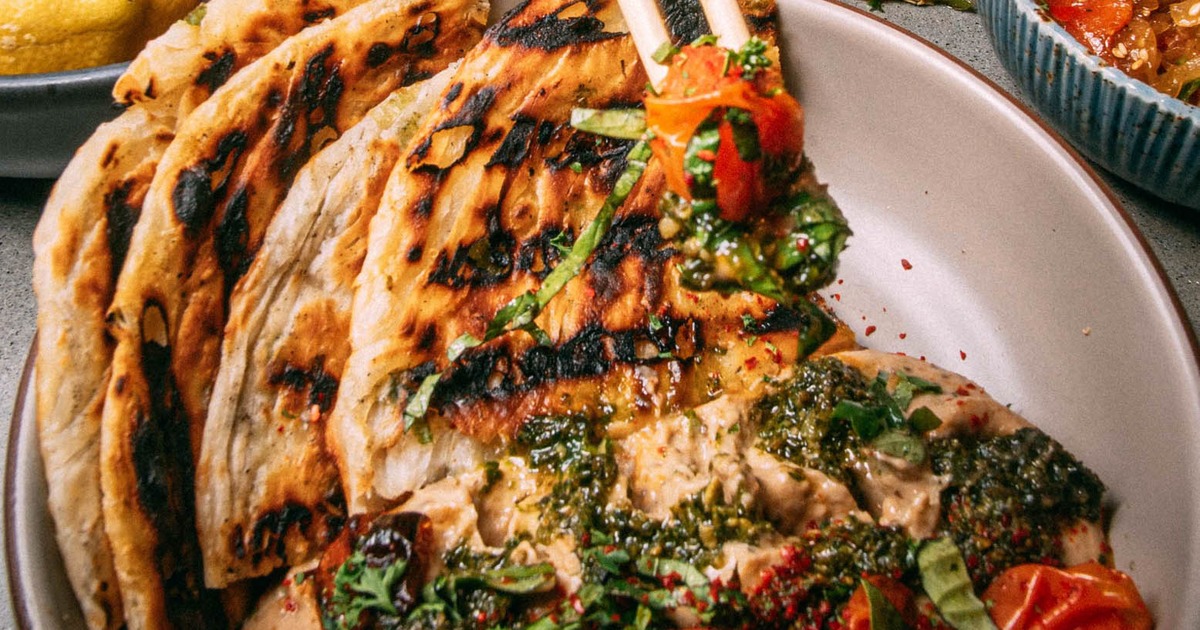 Flaky, charred flatbreads served with creamy dip and herb sauce