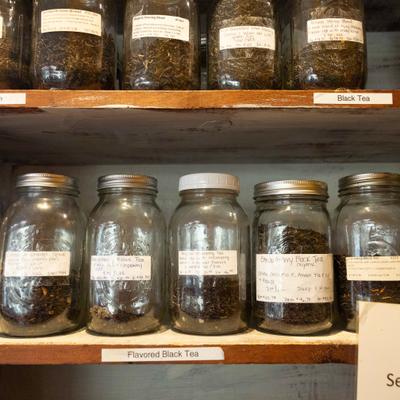 Numereus jars of loose tea on the wooden shelves.