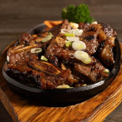 Korean BBQ short ribs served in a skillet with a wooden base.