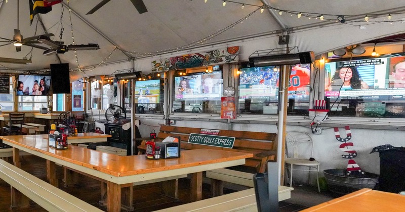 Inside, wooden tables, fairy lights, ceiling fans, and TVs on the walls