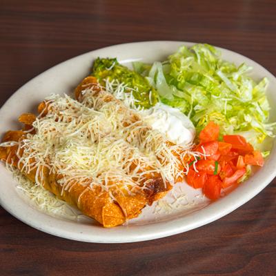 Crispy flautas topped with shredded cheese, served with guacamole, sour cream, and lettuce.