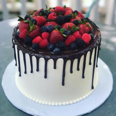 White cake with chocolate drip, topped with berries