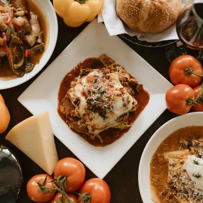 Various dishes served alongside fresh vegetables, cheese and red wine.