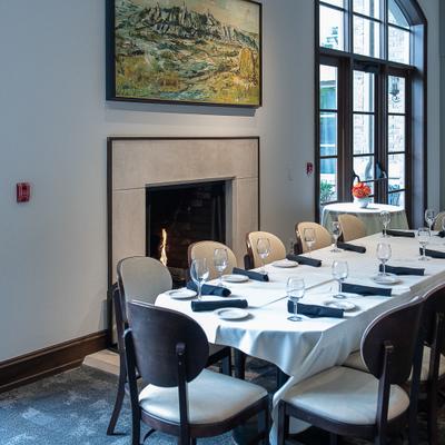 Dining area featuring a fireplace with a stone mantelpiece, framed art and table seating.