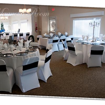 Formal dining room featuring white round tables and chairs with black sashes.