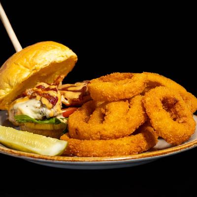 Chicken sandwich with bacon and spicy aioli, served with onion rings and a pickle spear.
