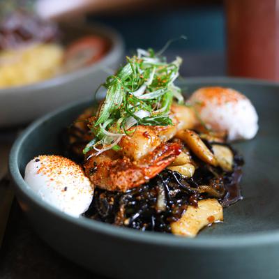 Handmade squid ink noodles with prawn, squid, sweet soy ginger, and poached eggs.