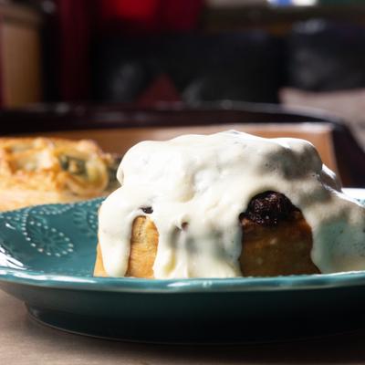 Cinnamon roll with cream cheese icing on a teal plate.