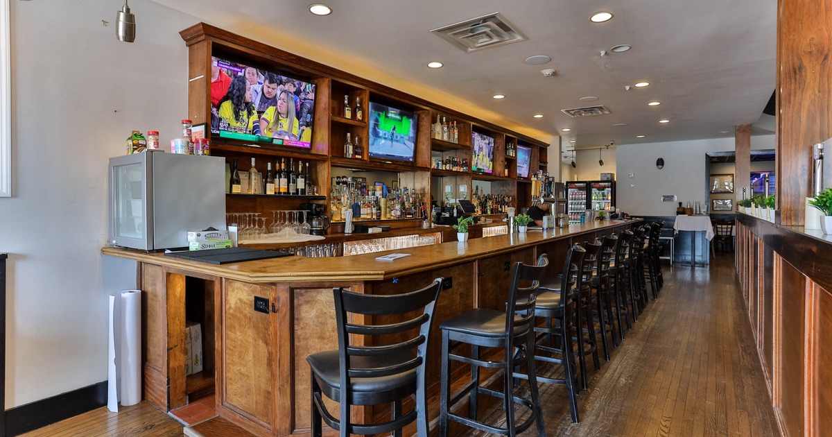 Interior, bar area, wooden top bar with bar stools, large wooden shelf behind the bar