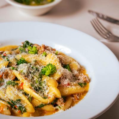 Pasta with broccoli and grated Parmesan cheese on a white plate.