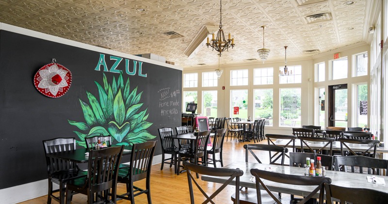 Interior of the restaurant with wooden tables and chairs, and large windows