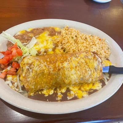 Chimichanga, smothered in cheese sauce, with rice, refried beans, lettuce, tomato, and onion.