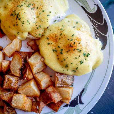 Eggs Benedict served with crispy breakfast potatoes, close-up.