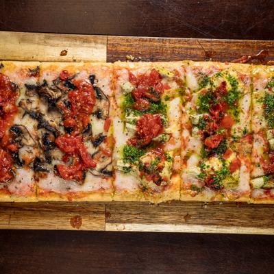 Half-and-half Roman-style pizza with mushroom and red sauce and artichoke and pesto sauce.